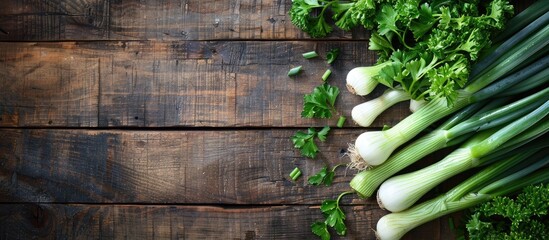 A top-down shot showing green onion, leek, and parsley on a wooden table, illustrating the concept of healthy eating with copy space image available.