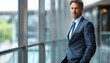 © Steven - A confident businessman in a navy suit stands by the window, gazing out, epitomizing professionalism and success in a modern corporate setting