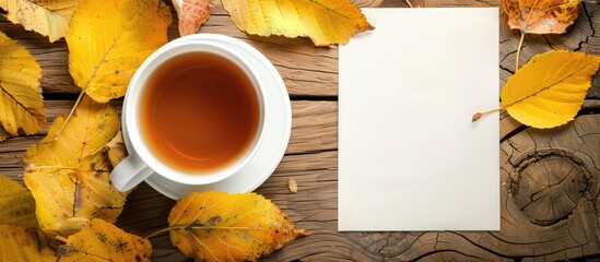 Poster - Autumn banner with a cup of warm tea, a blank sheet for captions, and a copy space image. Hot beverage set against a backdrop of yellow leaves.