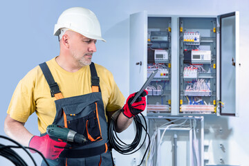 Poster - man is electrician. electrical engineer. master is standing near power panel. guy fixes electrical w