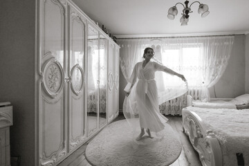 Wall Mural - A woman in a white dress is dancing in a room with white furniture. The room is dimly lit, giving it a romantic and intimate atmosphere