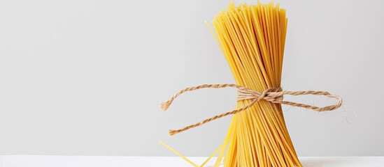 Poster - Closeup of a bundle of Italian long yellow spaghetti against a white backdrop with copy space image.