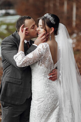 Wall Mural - A bride and groom are kissing each other's lips. The bride is wearing a white dress and the groom is wearing a suit