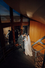 Wall Mural - A bride and groom are kissing on a staircase. The bride is wearing a white dress and the groom is wearing a suit. The scene is intimate and romantic