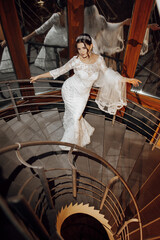 Wall Mural - A woman in a wedding dress is standing on a spiral staircase. She is wearing a veil and a tiara
