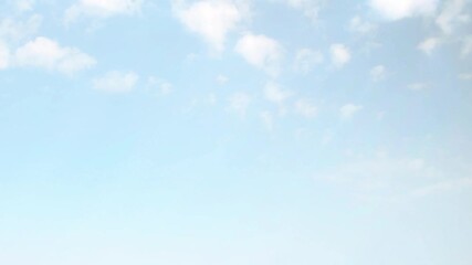 Wall Mural - Bright blue sky with small, fast moving clouds. Background with an atmospheric theme in soft, pastel colors.