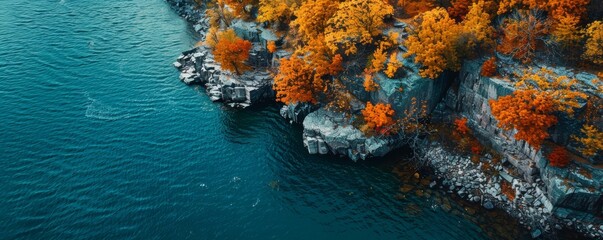 Wall Mural - Aerial view of rocky shoreline with autumn trees and turquoise water
