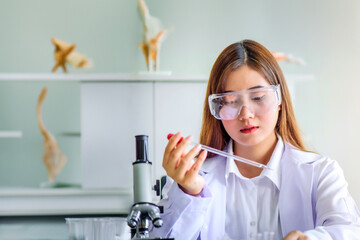 Wall Mural - attractive young asian scientist woman lab technician assistant analyzing sample in test tube at lab