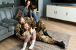 © Yakobchuk Olena - Rejoicing soldier man tickling cute little daughter at home
