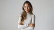 © SITI - Confident young woman with arms crossed, smiling in a casual white outfit against a plain background