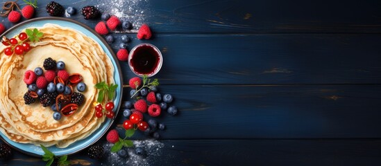 Leinwandbilder - Top view copy space image of European holiday Maslenitsa with traditional thin crepes adorned with berries, jam, and honey on a blue wooden table.