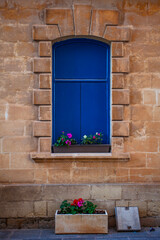 Traditional malta  stone house with blue window decorated with flowerpots