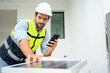 © bigy9950 - electrician man in safety vest with helmet use smartphone for check solar cell plant. Green energy electricity. concept of sustainable resources.