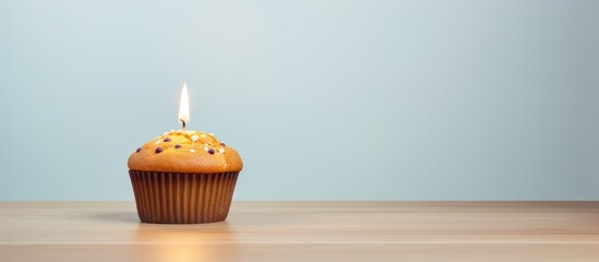 Aufkleber - Minimalist copy space image for a birthday celebration with a muffin and burning candle in the background, ideal for an anniversary greeting card.