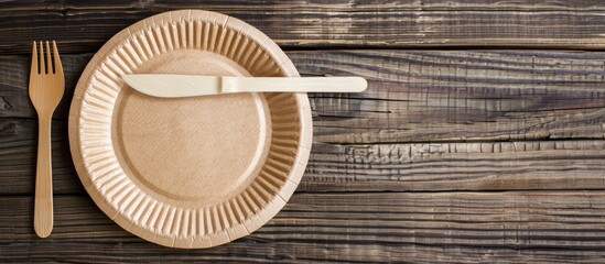 Poster - Empty brown paper plate and fork with knife on a wooden table. View from above. Eco-friendly disposable tableware. copyspace. Copy space image. Place for adding text or design