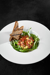 Sticker - Tuna Tartare with Arugula and Toast: Gourmet Presentation in White Plate on Dark Background