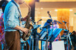 © JinnaritT - Musician playing saxophone on blurred background. Man with friends blow saxophone with the band for performance. Music instrument played by saxophonist player musician in festival. Selective focus.