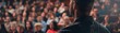 © May Chanikran - Speaker addressing a large audience in a seminar or conference setting. Focus on speaker with blurred audience in the background.