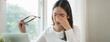 © Pormezz - Eye problem concept, fatigue asian young woman tired eyes, irritated rubbing eye dry relief vision pain after work on laptop computer, eye strain, hand holding glasses, suffer migraine, bad blurry