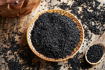 Wall Mural - Black cumin or Nigella sativa seeds in a wooden bowl. Healthy nutritional supplement.
