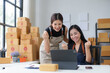 © amnaj - Two excited female business owners celebrating success looking at laptop in warehouse office