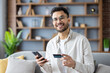 © Tetiana - Smiling man holding phone and credit card making online purchase