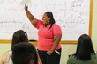 © AdPremium - Young plus size Latina student standing in the classroom holding a paper and celebrating.