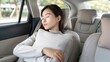 © lililia - A woman sleeps peacefully in the back seat of a car, holding a pillow