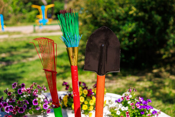 Three gardening tools are displayed in a garden setting