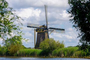 Wall Mural - Spring landscape view with beautiful traditional windmill under blue sky, Dutch agriculture in countryside with corn or maize field along the Vecht river, Nigtevecht, Province of Utrecht, Netherlands.