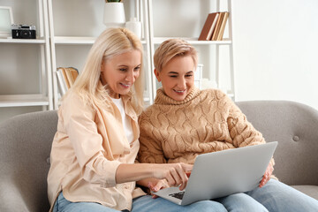 Sticker - Happy mature women with laptop sitting on sofa at home