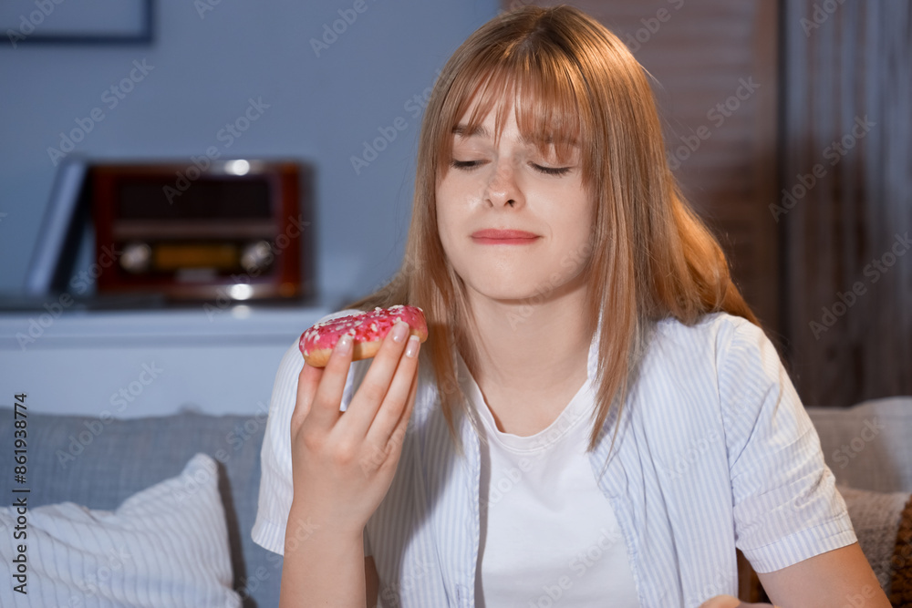 Young woman with tasty doughnut at night, closeup