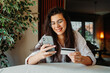 © Dusan - One young caucasian woman is buying online on her mobile smart phone using credit card from her home