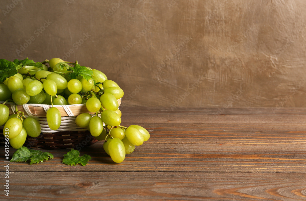 Basket with juicy green grapes on wooden background