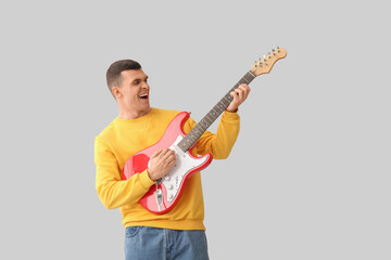 Canvas Print - Cool young man playing electric guitar on light background