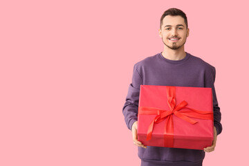 Wall Mural - Handsome man with gift box on pink background
