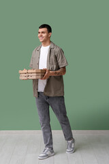 Sticker - Young man holding cardboard boxes with tasty pizza near green wall