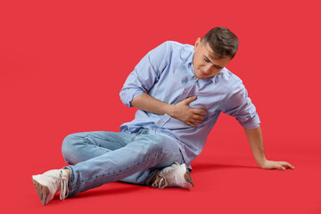 Canvas Print - Young man suffering from chest pain on red background