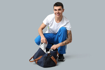 Wall Mural - Young man with sports bag on grey background