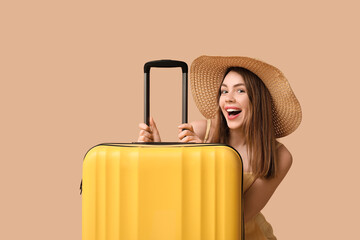 Sticker - Happy young woman with yellow suitcase on brown background