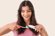 © Pixel-Shot - Smiling young woman pouring tooth paste onto brush on light background, closeup