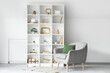 © Pixel-Shot - Shelf unit with artificial plants and armchair in living room