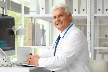 Canvas Print - Mature doctor sitting at table in clinic