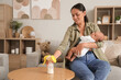 © Pixel-Shot - Mother with her baby taking breast pump from table at home