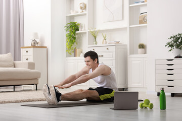 Wall Mural - Online fitness trainer. Man doing exercise near laptop at home