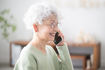 Wall Mural - close-up of smiling elderly (senior) woman in profile holding and talking on her cell phone (cell ph