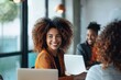 © LifeMedia - A smiling woman sits with a laptop open in front of her in a modern office meeting, suggesting productivity and a positive, collaborative work environment.