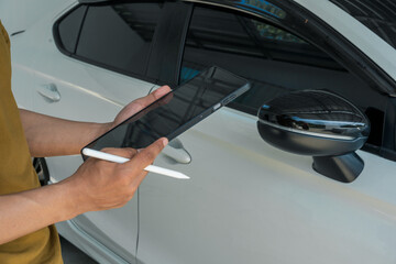 A businessman stands next to his damaged vehicle after an accident, holding a clipboard and examining the scene. An insurance agent arrives to assess the damage and start the claim process.