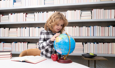 Fototapete - School and students in classroom. Education kids. Child pupil student in the school class. Studying and learning concept. School boy in the library near school supplies. Kid learn geography with globe