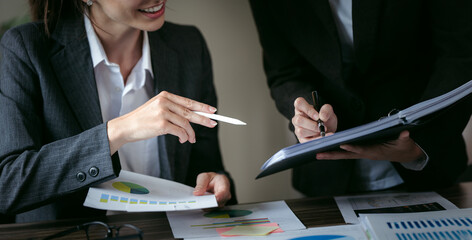 Wall Mural - Two businesswoman pointing to graphs and charts to analyze market data,  net profit to plan new sales strategy to increase production capacity.